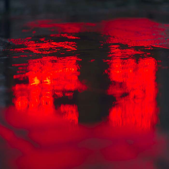 red traffic lights reflecting off a wet pavement